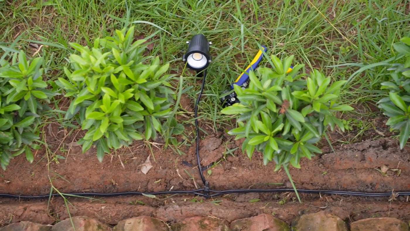 Top-down T-junction near a spotlight; electrical wire for outdoor lighting products links branch runs using waterproof connectors.