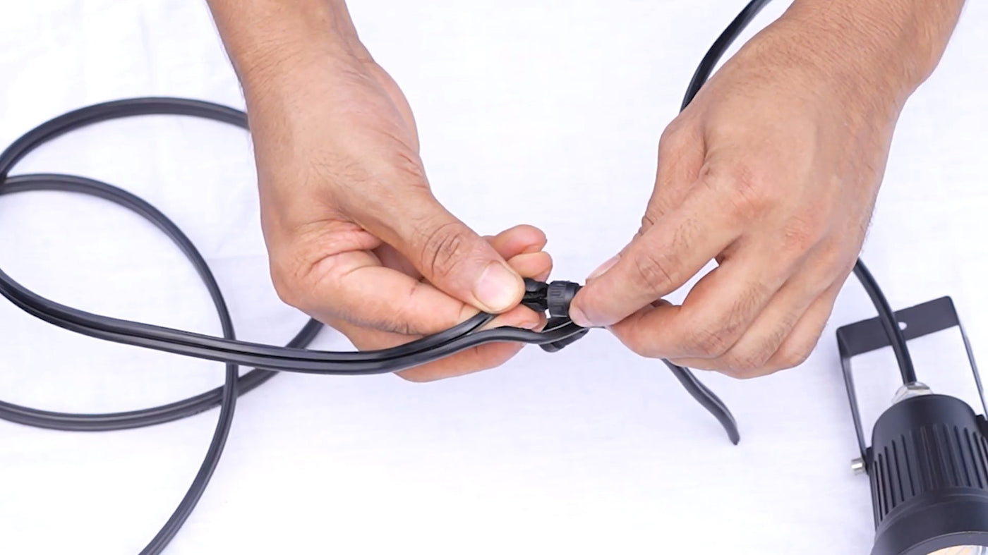 Low volt wire connection being secured by hand, ensuring reliable low voltage outdoor lighting for landscape projects.