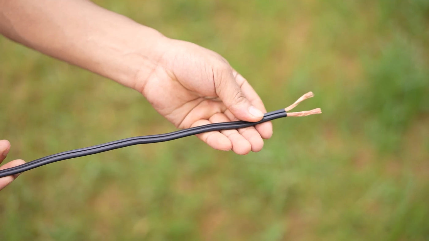 Durable low voltage wite with exposed copper ends shown in outdoor use, suitable for garden and pathway lighting systems.