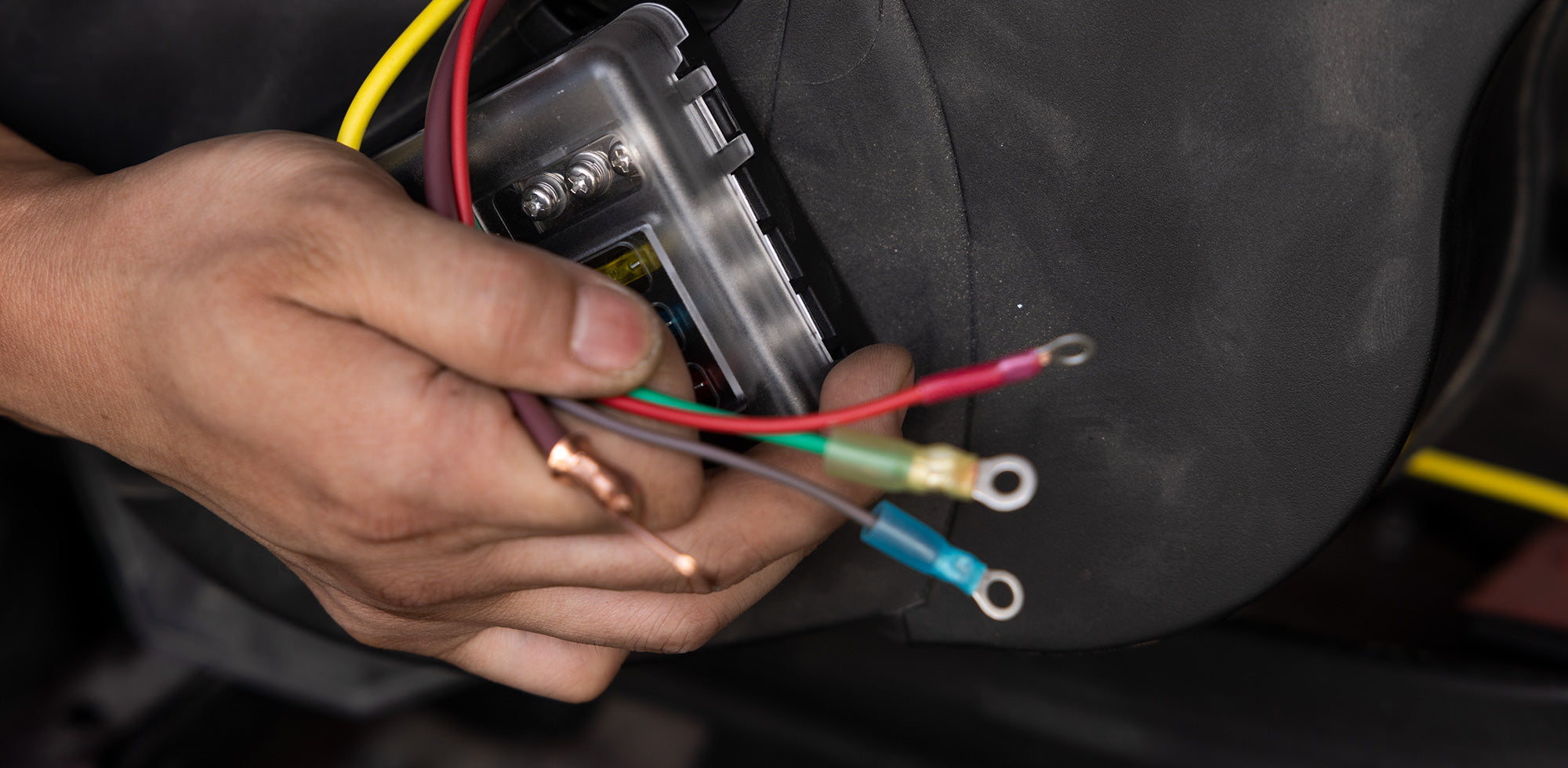 Hands stripping and connecting automotive wires with heat shrink connectors