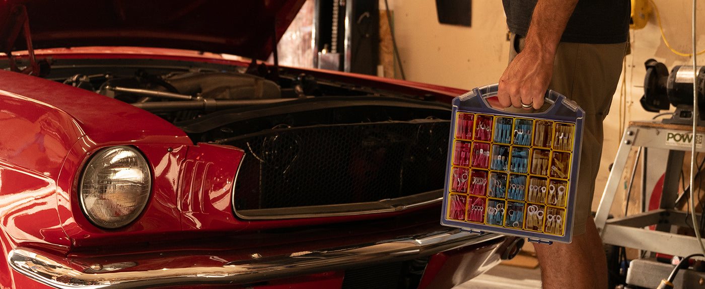 Marine wiring connectors set carried to a garage workspace, suitable for automotive and marine electrical repairs requiring sealed connections.