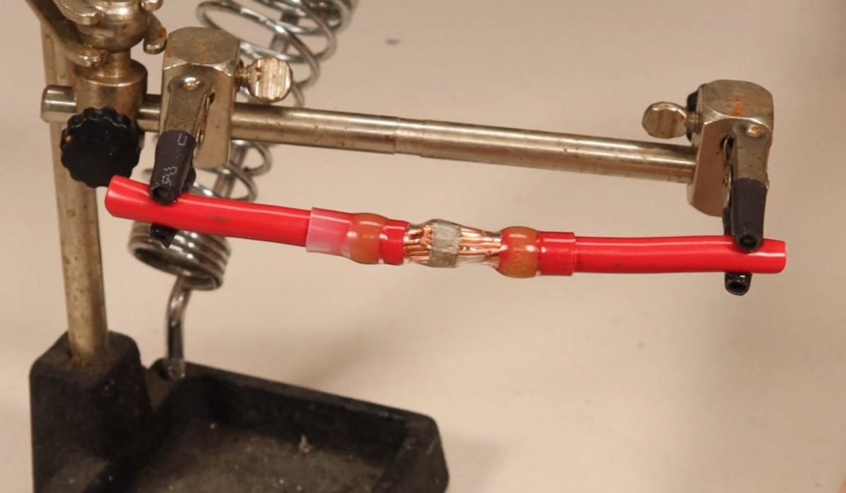 Heat-shrink wire connection being assembled on a workbench
